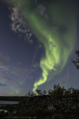 Eine Aurora tanzt in der Abenddämmerung. Trotz eines noch relativ hellen Himmels ist das Naturphänomen gut sichtbar.